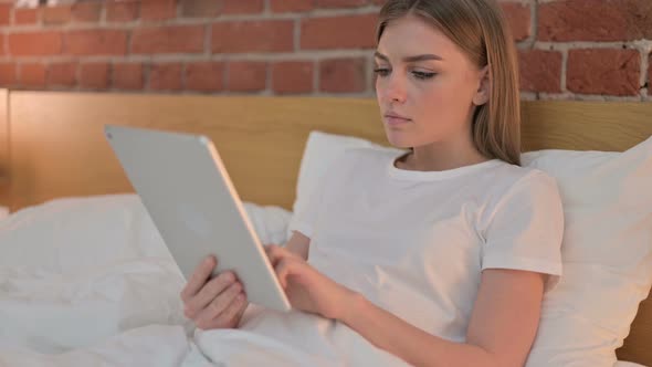 Cheerful Young Female Celebrating Success on Tablet in Bed