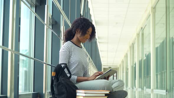 African American Woman Student Sitting on the Floor Use a Tablet in the University. New Modern Fully