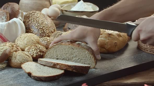 Hands Cutting the Baked Dutch Bread on the Table