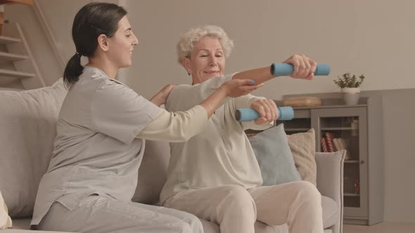 Social Worker Helping Senior Woman to Do Physical Exercises