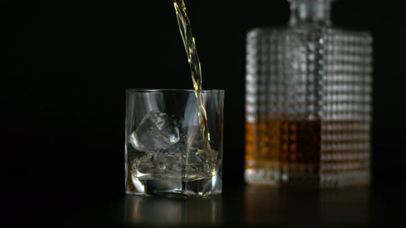 Slow Motion of Pouring Alcohol in Glass with Ice Whisky Bottle in Black Background