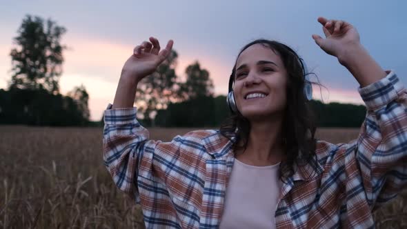 Slow Video of Woman in Plaid Shirt Listening To Music with Headphones and Dancing Outdoors at Sunset