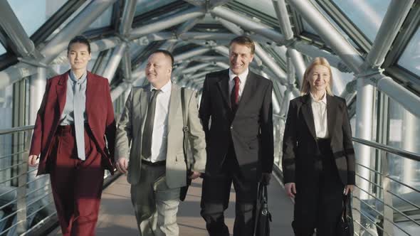 Successful Business Team Walking Along Glass Bridge