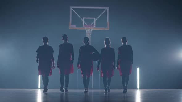 Slow Motion Performance Team of Basketball Female Players Walks Through the Gym in Contour Lighting