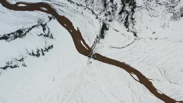 Drone Over Snow Covered Landscape With Frozen Braided Riverbed