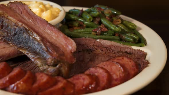 Texas barbecue plate, ribs sausage brisket with green beans and macaroni and cheese, close up slider