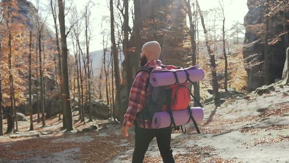 Man with Backpack on His Shoulders Descends from a High Mountain Path