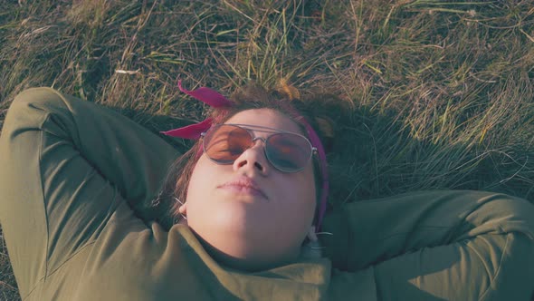 Plus Size Woman Lies on Fresh Grass at Campsite in Evening