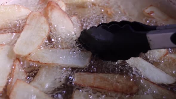 Close up of potatoes frying on hot boiling oil. Home made french fries fried in oil.