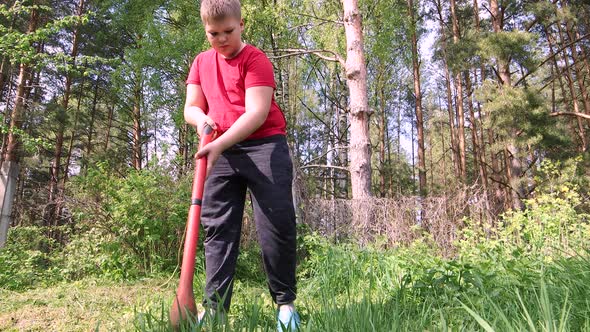 A Boy Mows Tall Green Grass with an Electric Trimmer