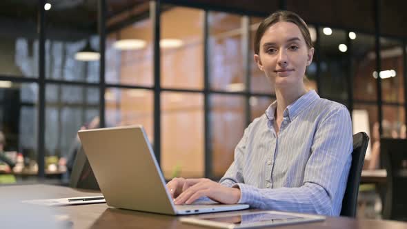 Woman Smiling Toward Camera While Working on Laptop