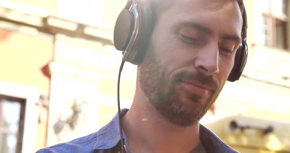 Close Up Portrait of Young Attractive Man enjoying Music, Using his Smartphone.