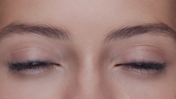 Close-up portrait of young, beautiful and natural woman opening her eyes.