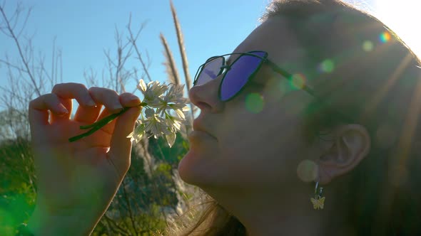 A woman smells a flower. A dream come true portrait at sunset. Girl silhouette with sunglasses