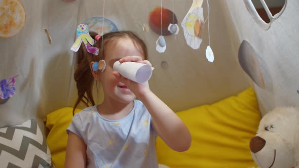 Little Girl Astronaut Looks at the Planets Through a Homemade Spyglass