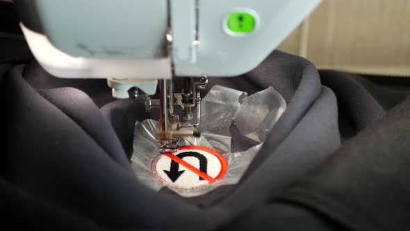 Embroidery machine is creating No turning back traffic sign on a gray fleece fabric