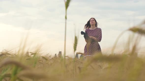 Beautiful Young Woman Walks in a Wheat Field