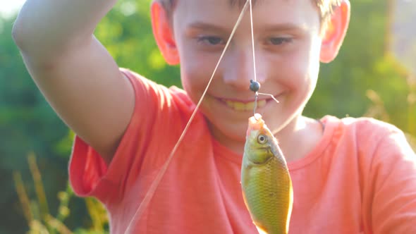 Portrait of a smiling Caucasian boy 7-8 years old showing a freshly caught fish. The boy is fishing 