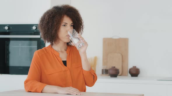 Thirsty Ill Slim African American Woman with Curly Hair Girl in Home Kitchen Drinking Water in