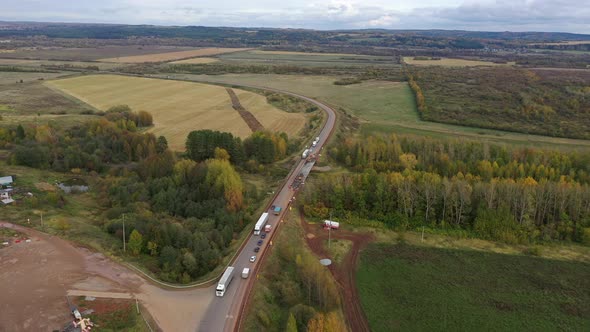 Aerial Drone View Road Repair Work and Meadow Landscape. Trucks on Road Driving Away in Beautiful