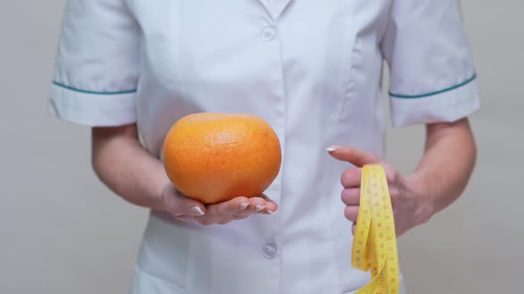 Nutritionist Doctor Healthy Lifestyle Concept - Holding Organic Grapefruit Fruit and Measuring Tape