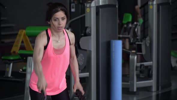 Young Sportive Brunette Woman Trains with Ropes in the Gym