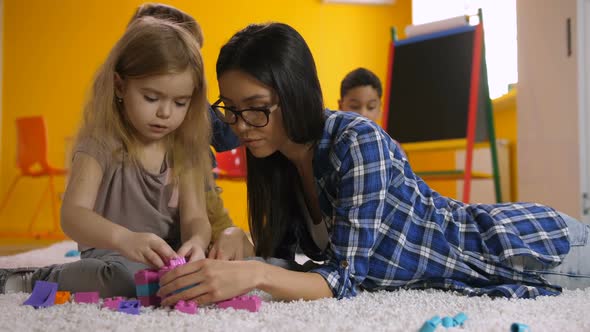 Teacher Helps Child with Construction Toy Blocks