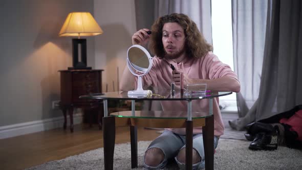 Middle Shot of Adult Caucasian Intersex Person Looking at Mirror As Doing Makeup. Man Holding