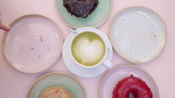 Assorted Vegan Doughnuts Served Around Cup of Matcha Latte on Pastel Pink Table