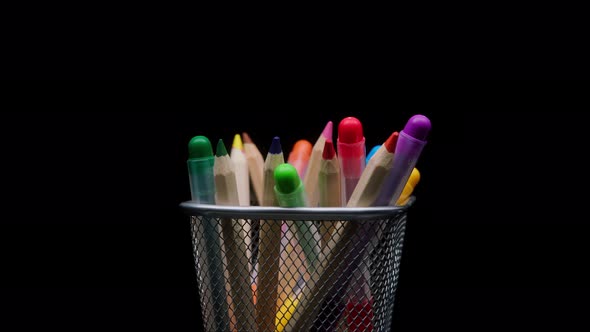 Closeup of Colored Pencils and Markers in a Metal Grey Basket Shooting Stationery on Black