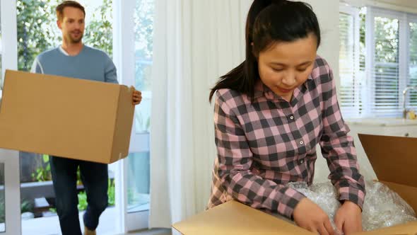 Pregnant couple unpacking boxes in their new house 4k