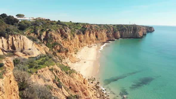 Secluded sand beach surrounded by cliffs, Lagos, Algarve. Aerial forward.