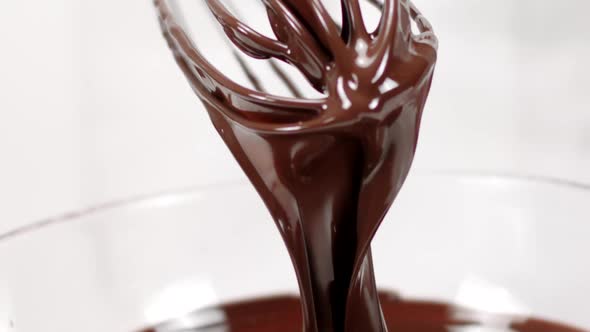 Chef Takes Whisk Out of Melted Chocolate. Chocolate Streams Flow Down Slow Mo