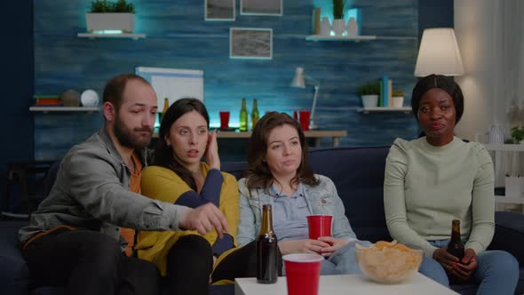 Group of Mixed Race Friends Relaxing on Sofa While Watching Entertainment Movie on Television