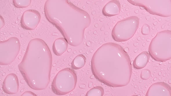 Macro Shot of Cosmetic Moisturizing Drops of Liquid on a Pink Pastel Background