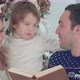Happy Father Reading About Santa Beard, While Mother Holding Their Playful Son - VideoHive Item for Sale
