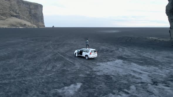 Man on Top of White Van with Sea Stack and Cliff in View