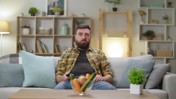 Young Handsome Man Sitting on a Couch at Home and Watching Tv