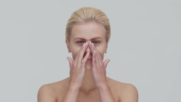 Studio portrait of young, beautiful and natural blond woman applying skin care cream. F