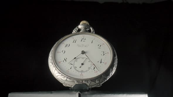 Gold Antique Pocket Watch on a Stand Zooming on a Black Isolated Background