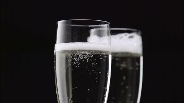 Filled with Two Glasses of Champagne with White Bubbles on a Black Background. Close Up