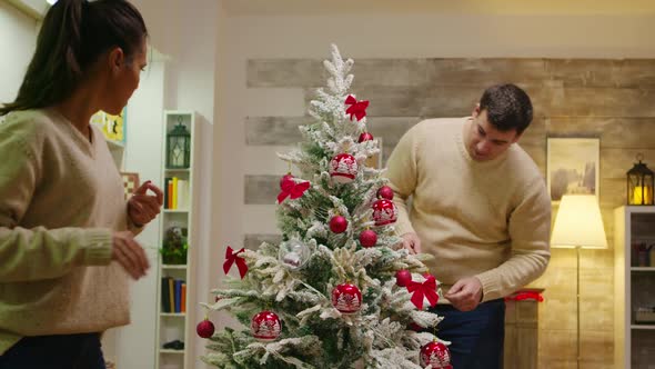 Young Man and Woman Decorate Their Christmas Tree