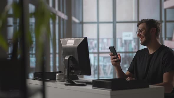 Smiling Young Guy Using Mobile Apps Sit at Table