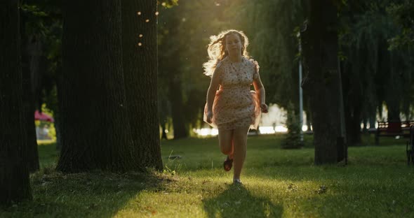 Cheerful Young Girl Running To Camera in Summer Park
