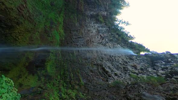 Vertical shot of a waterfall with a sharp rock wall cliff face.