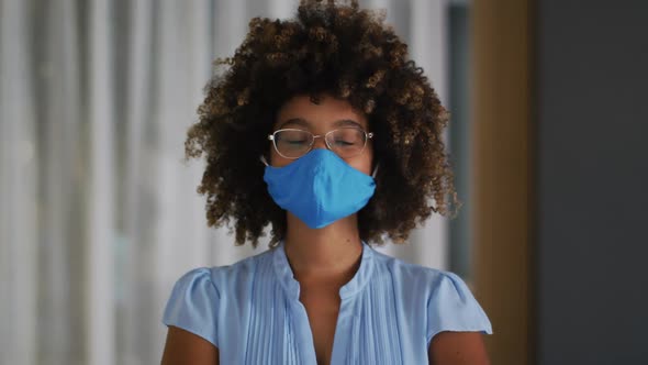 Portrait of mixed race woman with curly hair wearing blue face mask