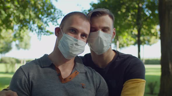 Same-sex Couple in Medical Masks Kissing Outdoors