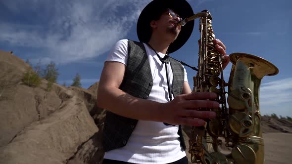 Portrait of a Musician in a Hat Playing Jazz on a Saxophone Standing in the Desert Against a