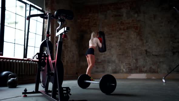 Blonde Woman Is Practicing Box Fight in Gym, Punching Bag By Hands, Training