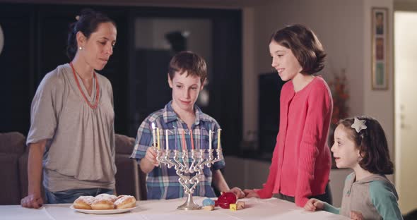 Kids and their mother lighting Hanukka candles